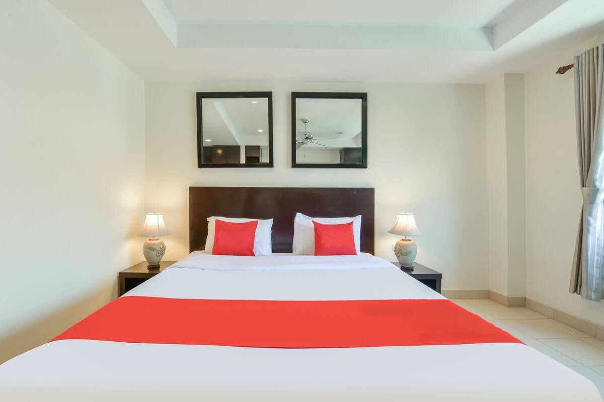 A hotel room with a large bed, two bedside tables, and two wall-mounted mirrors.