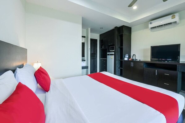 A hotel room with a bed, a TV, a kitchenette, and an air conditioning unit. - M Place Pattaya (Pattaya)