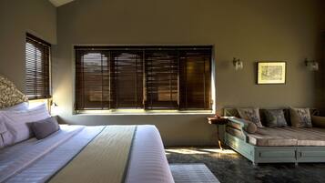 Quarto com uma cama grande, um sofá e uma janela com persianas.