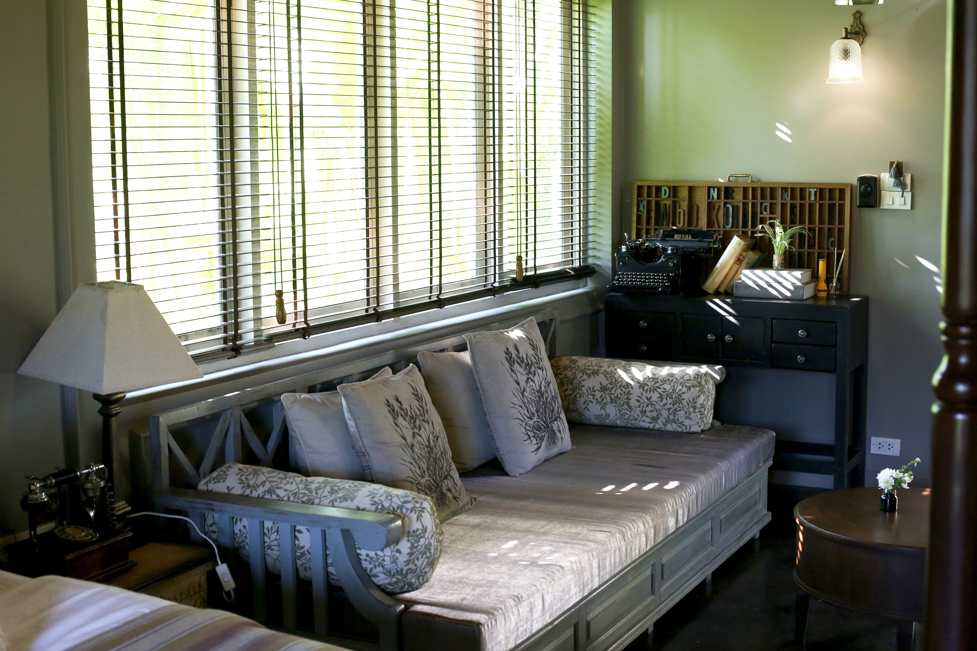 A bedroom with a bed, a nightstand, a dresser, and a window with blinds.