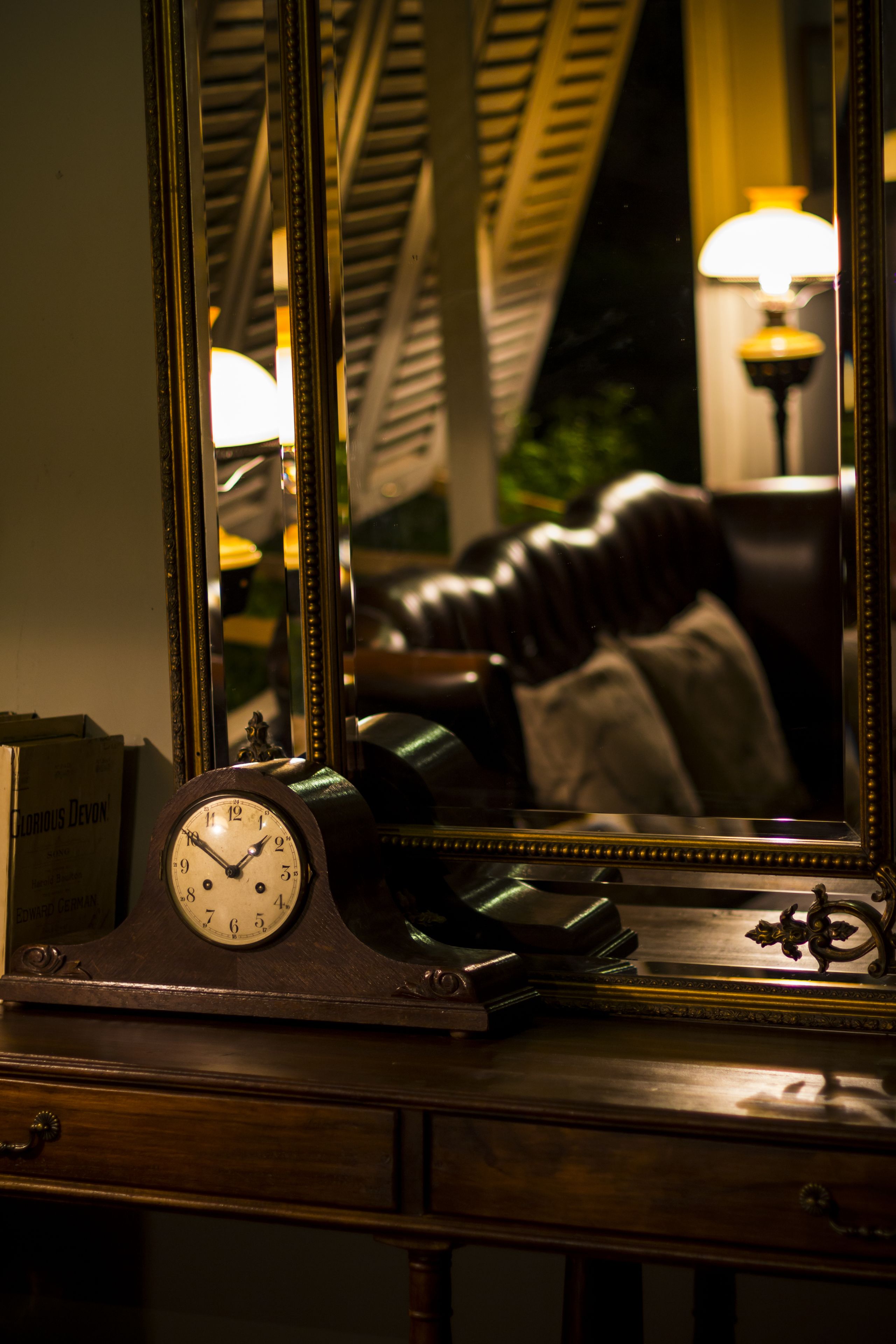 A wooden dresser with a clock and a mirror.