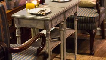 Een eethoek met een houten tafel gedekt voor twee personen, gestreept bekleden stoelen en een kaars op de tafel.