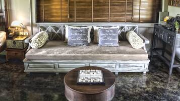 A vintage-style sofa with decorative pillows, a small round table with a tray of glasses, and a wooden cabinet with drawers.