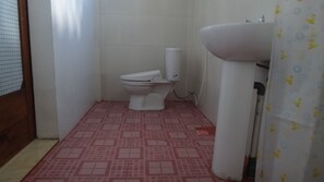 A small bathroom with a toilet, a sink, and a shower curtain. - Krisna Home Stay (Kuta)