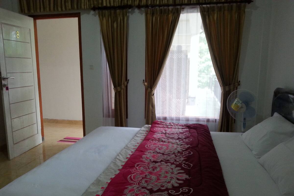 Un dormitorio con cama, cortinas, ventilador y puerta.