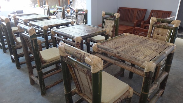 A room with several traditional bamboo chairs and tables, arranged in a casual setting.