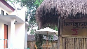 Una estructura con techo de paja y un cartel que dice "Krishna Lodge".