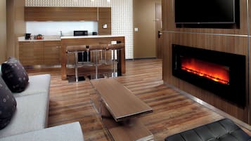 A modern living room with a sofa, a coffee table, a fireplace, and a kitchen area in the background.