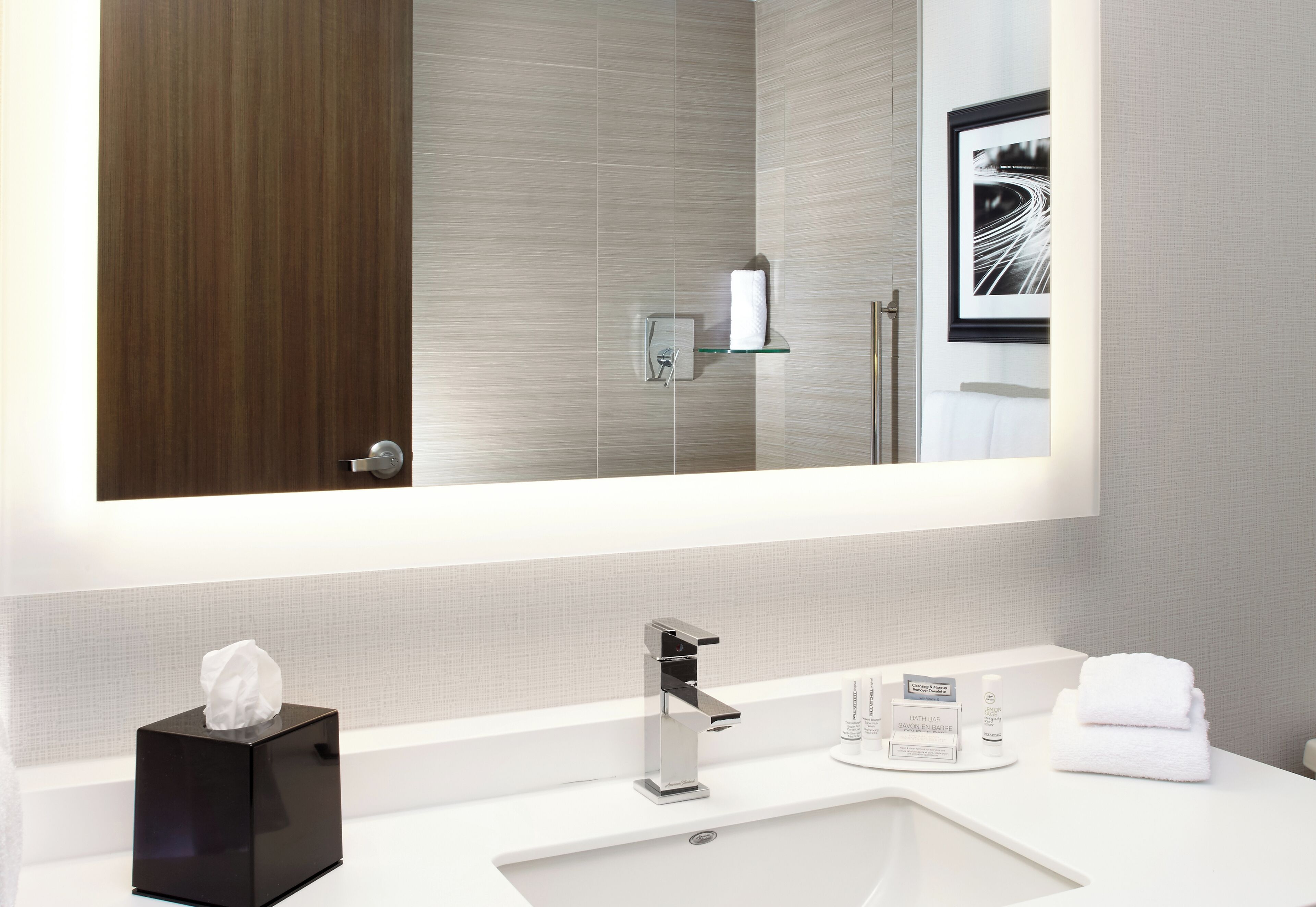 A modern bathroom with a large mirror, a white sink, and a glass shelf.