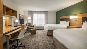 Une chambre d’hôtel avec deux lits, un bureau avec une chaise, une petite table, une chaise et un téléviseur.