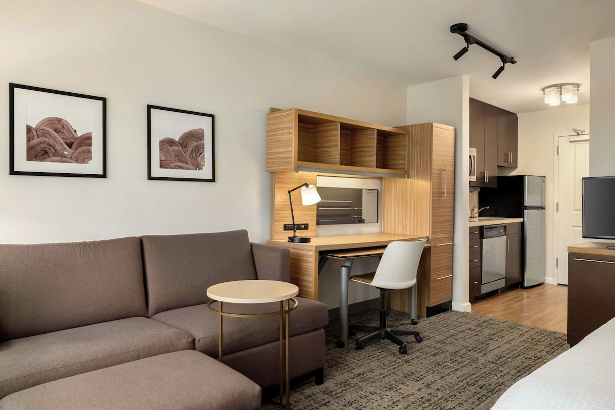 Une chambre d’hôtel moderne équipée d’un canapé, d’un bureau, d’une chaise et d’une kitchenette.