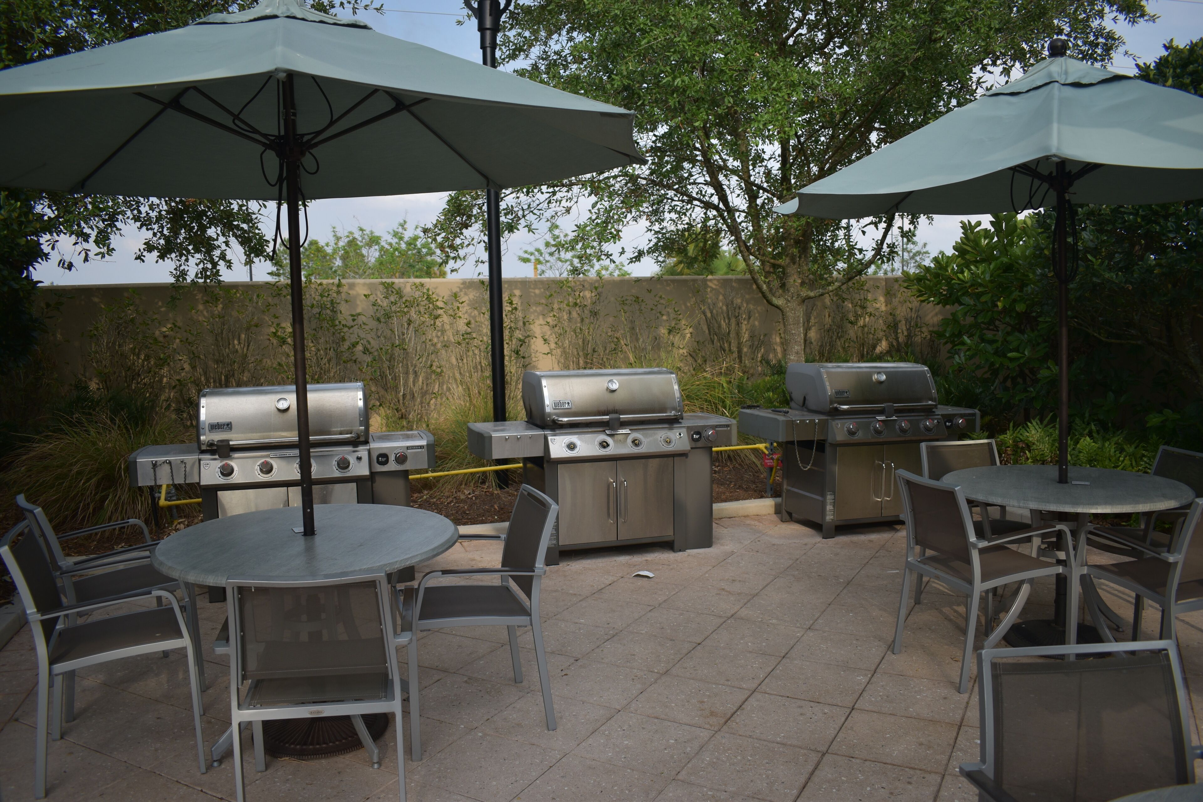 An outdoor patio with two barbecue grills, a round table, and four chairs.