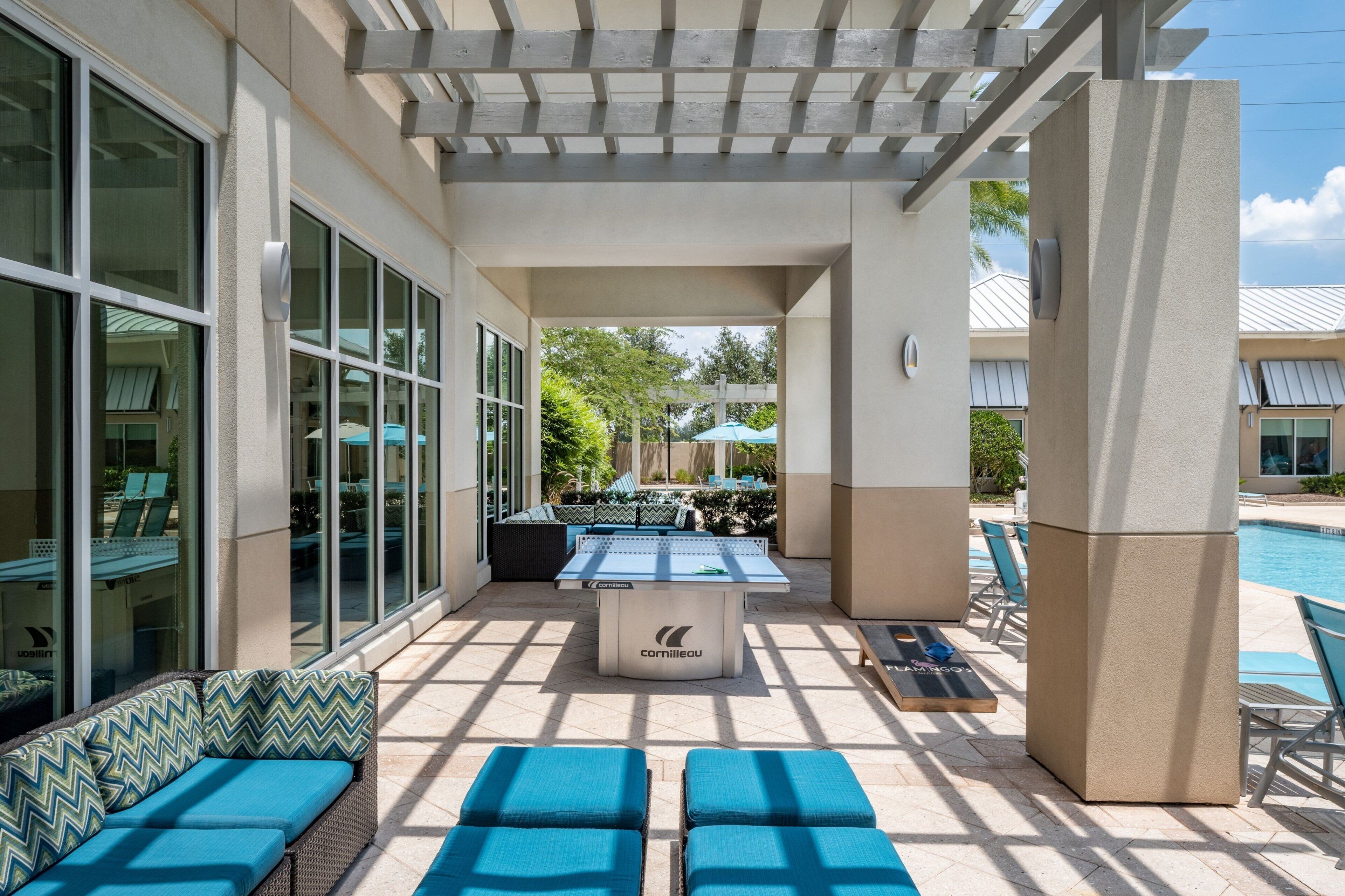 An outdoor pool area with lounge chairs and a foosball table.