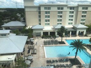 Un hotel con piscina, mobiliario exterior y una zona cubierta con sombrillas.