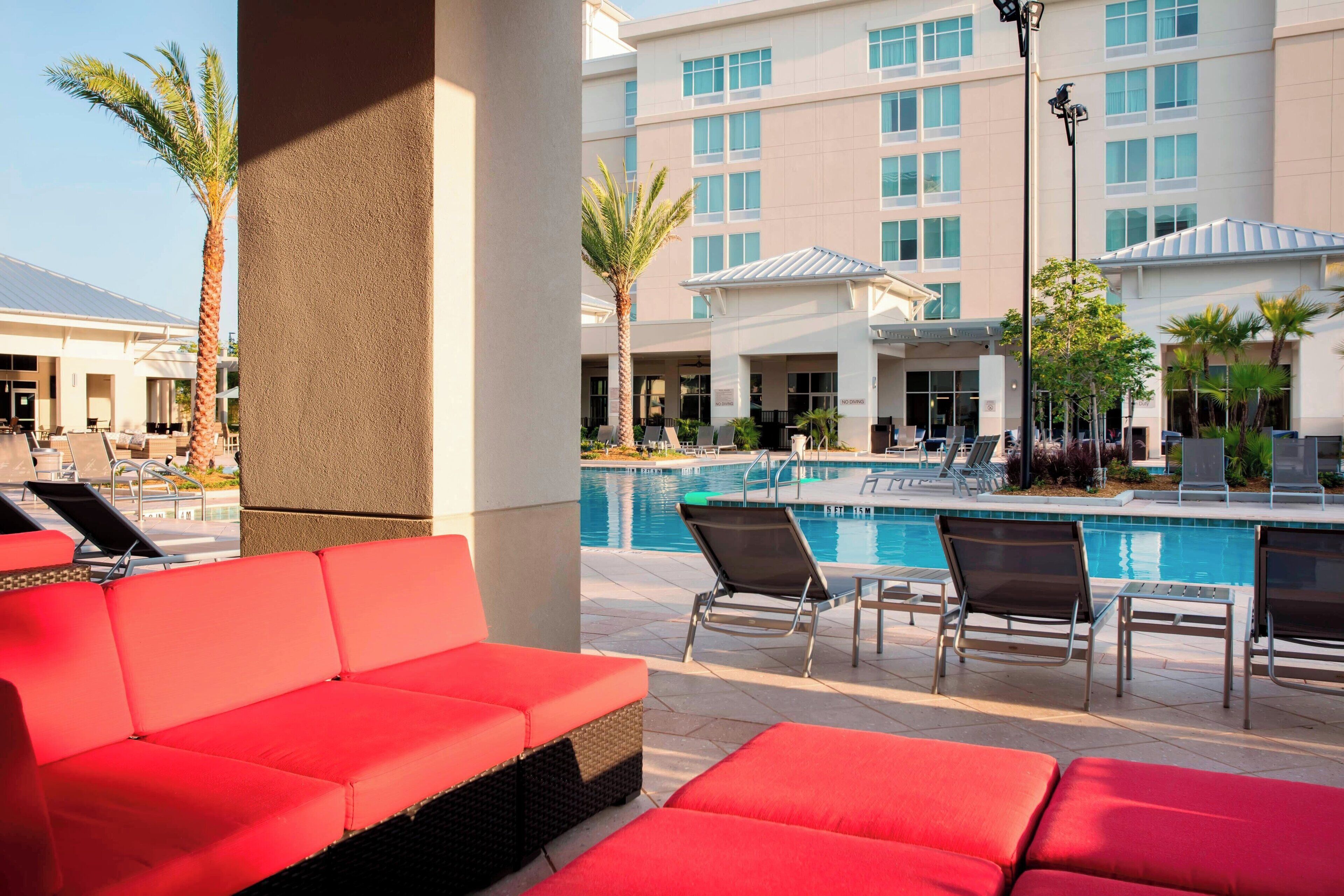 A pool area with red lounge chairs and a pool.