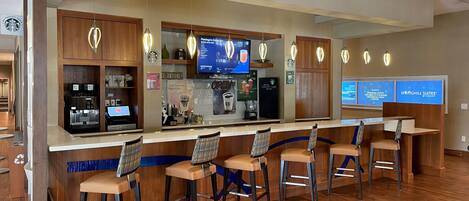 Un bar de café con diversas opciones de asientos y una pantalla digital mostrando el menú.