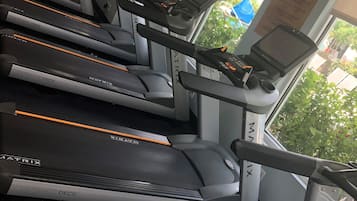 A row of MATRIX treadmills with a digital display and control panel, positioned in a well-lit room with large windows.