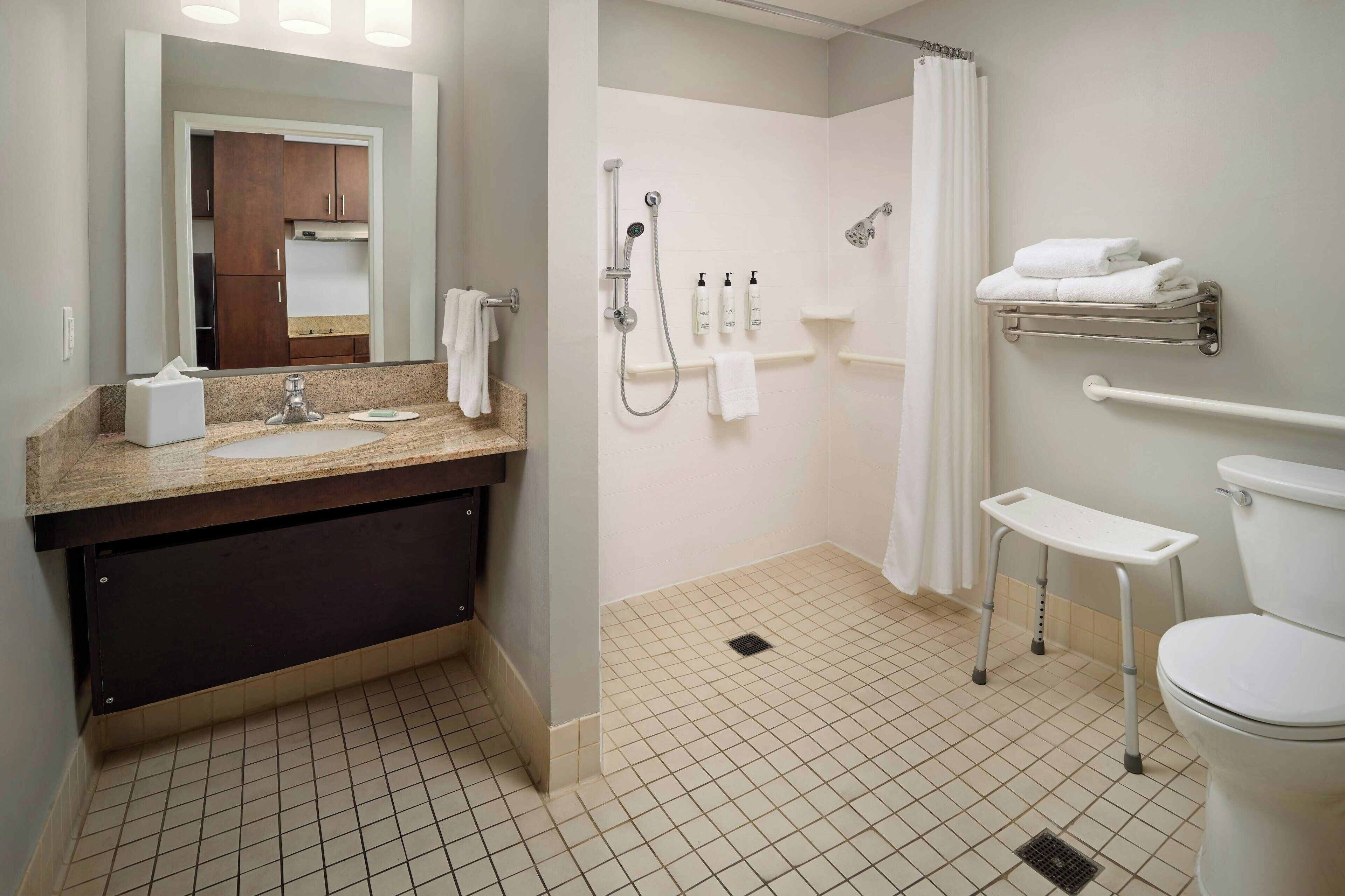 A modern bathroom with a sink, mirror, shower, toilet, and towel rack.