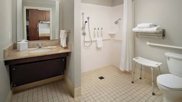A modern bathroom with a sink, mirror, shower, toilet, and towel rack.