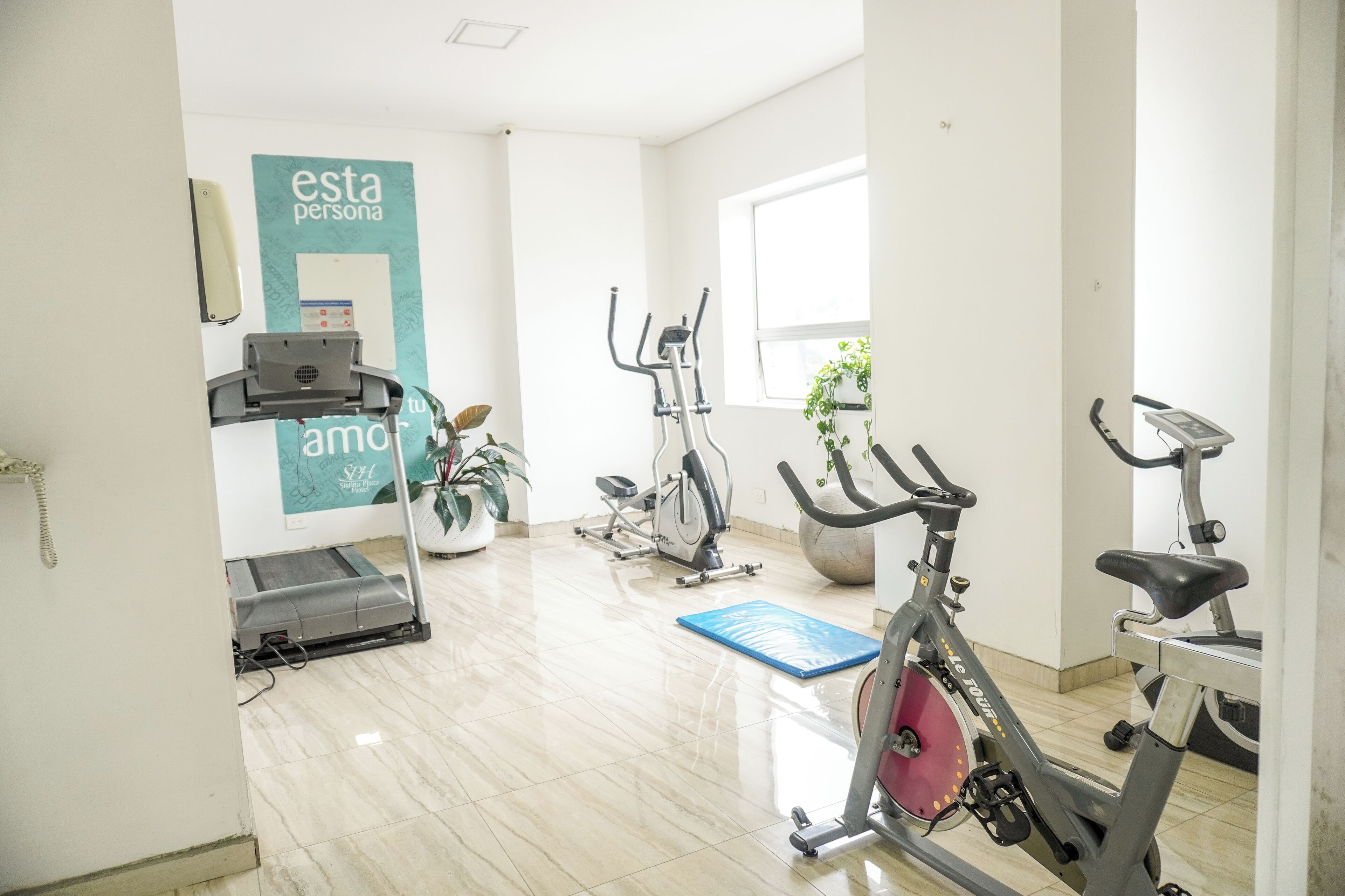 Un gimnasio con equipo de ejercicio, una cinta de correr y una bicicleta estática.