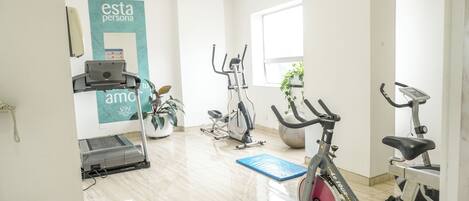Un gimnasio con equipo de ejercicio, una cinta de correr y una bicicleta estática.