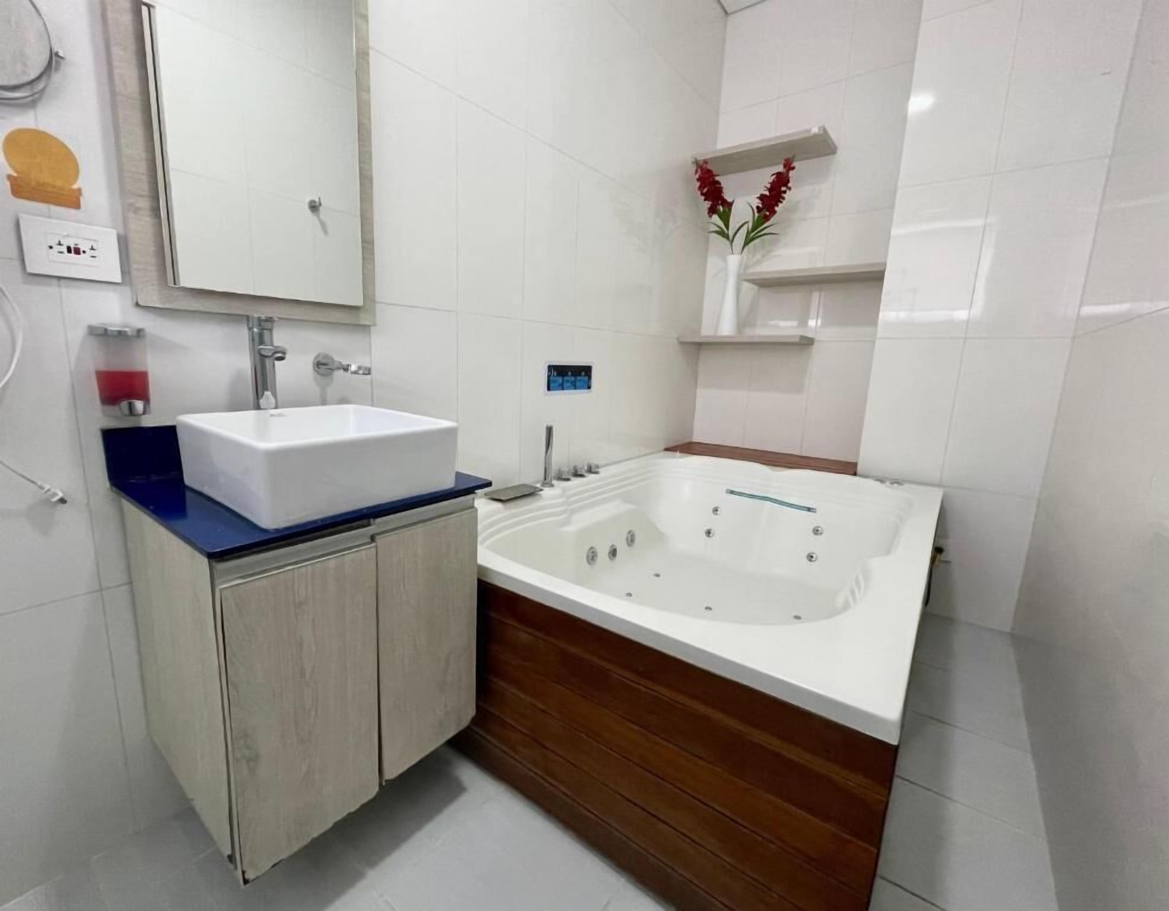 A modern bathroom with a white sink, wooden vanity, and a large bathtub.