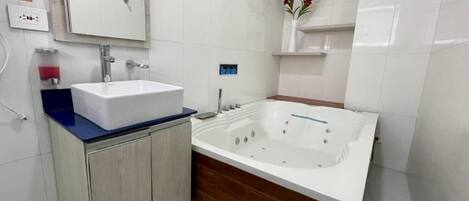 A modern bathroom with a white sink, wooden vanity, and a large bathtub.