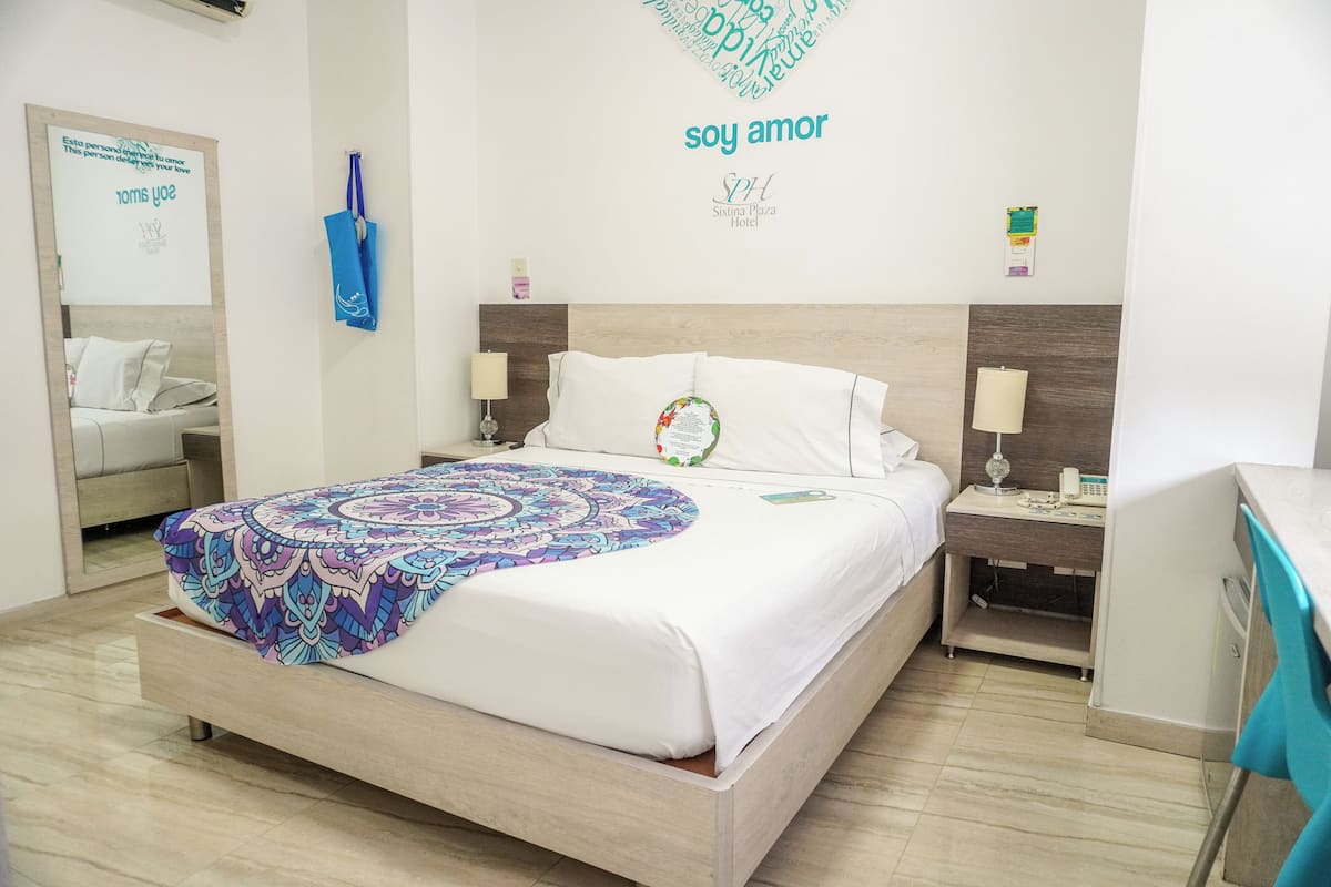 Une chambre d’hôtel avec un lit, des tables de chevet, un bureau et une chaise.