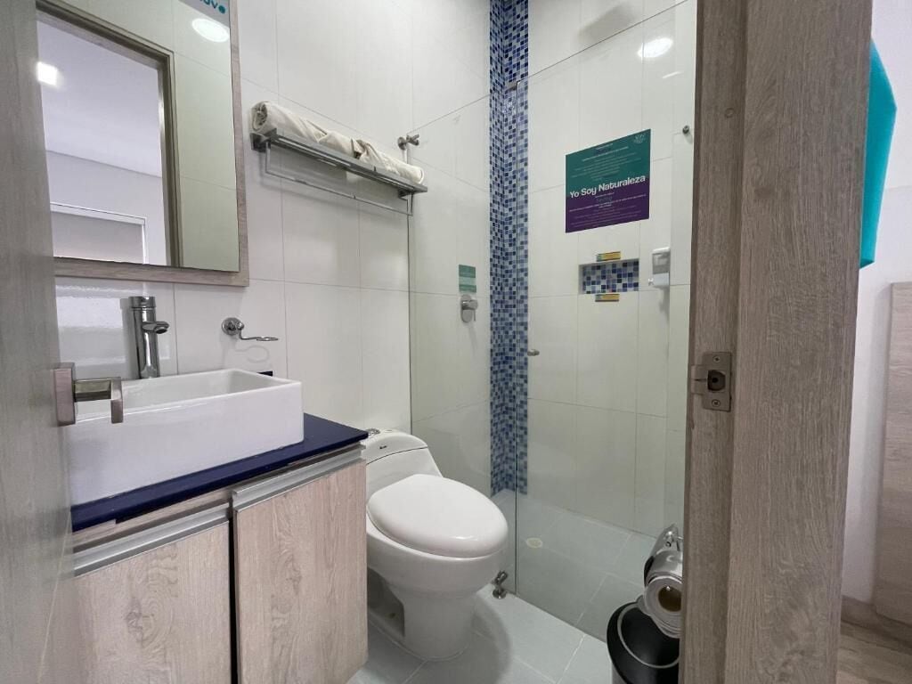 Un baño moderno con un lavamanos blanco, un inodoro y una cabina de ducha de vidrio.