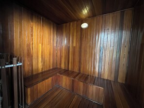 Een houten kamer met een bank, een plafondlamp en een deur.