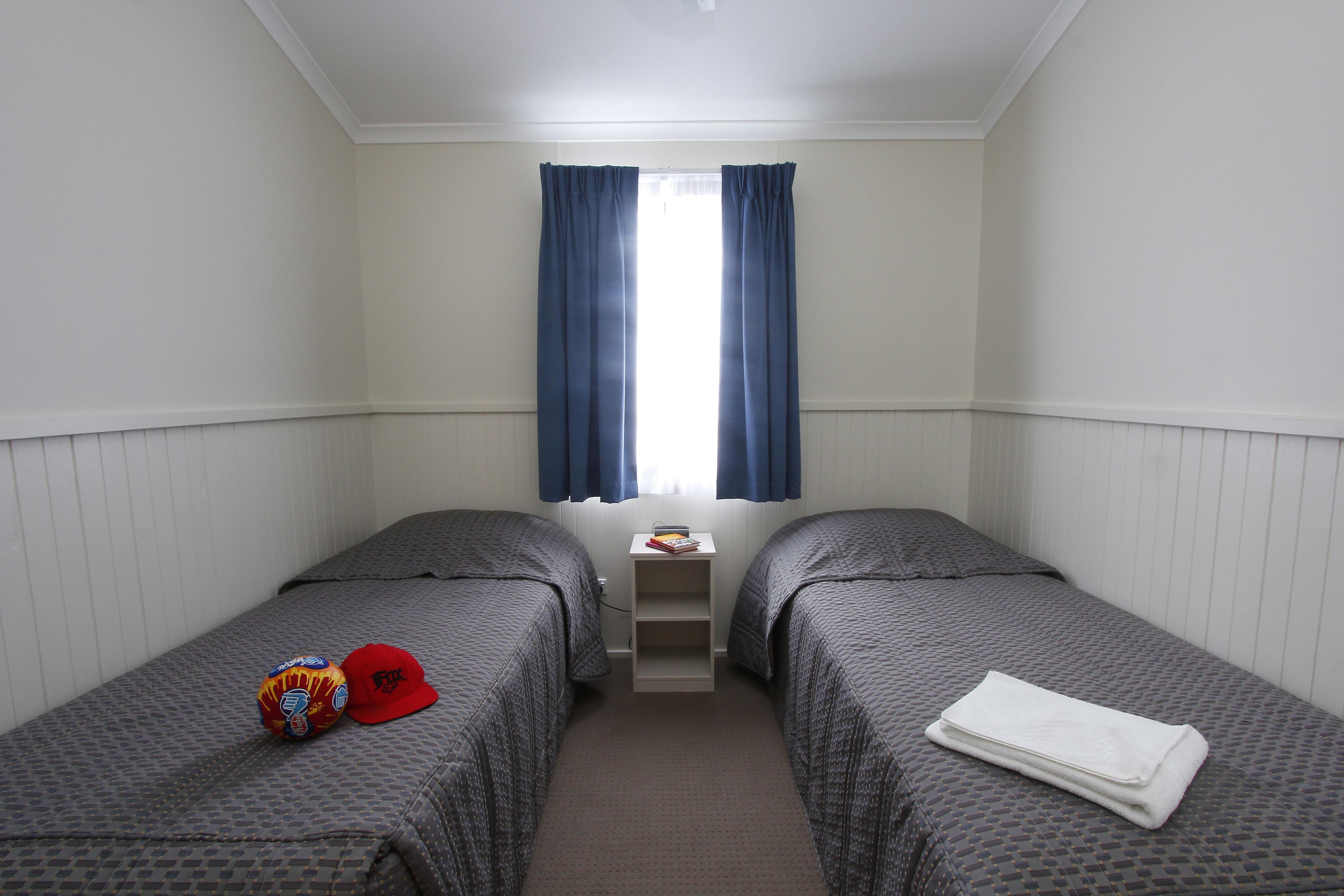 A twin room with two beds, a small table, and a window with curtains.
