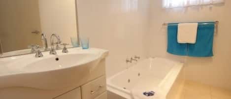 A bathroom with two sinks, a bathtub, and a window with curtains.