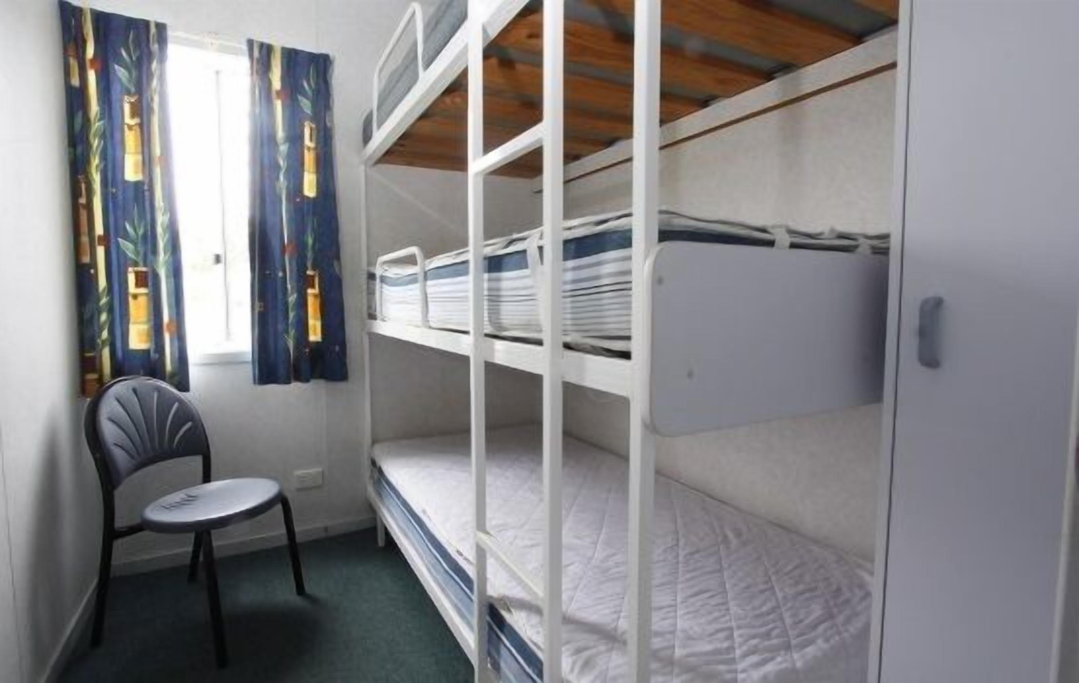 A bunk bed room with a chair and curtains.