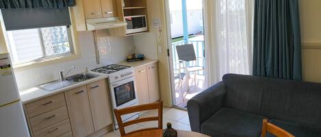 Cocina compacta con comedor, sofá y vista al exterior.
