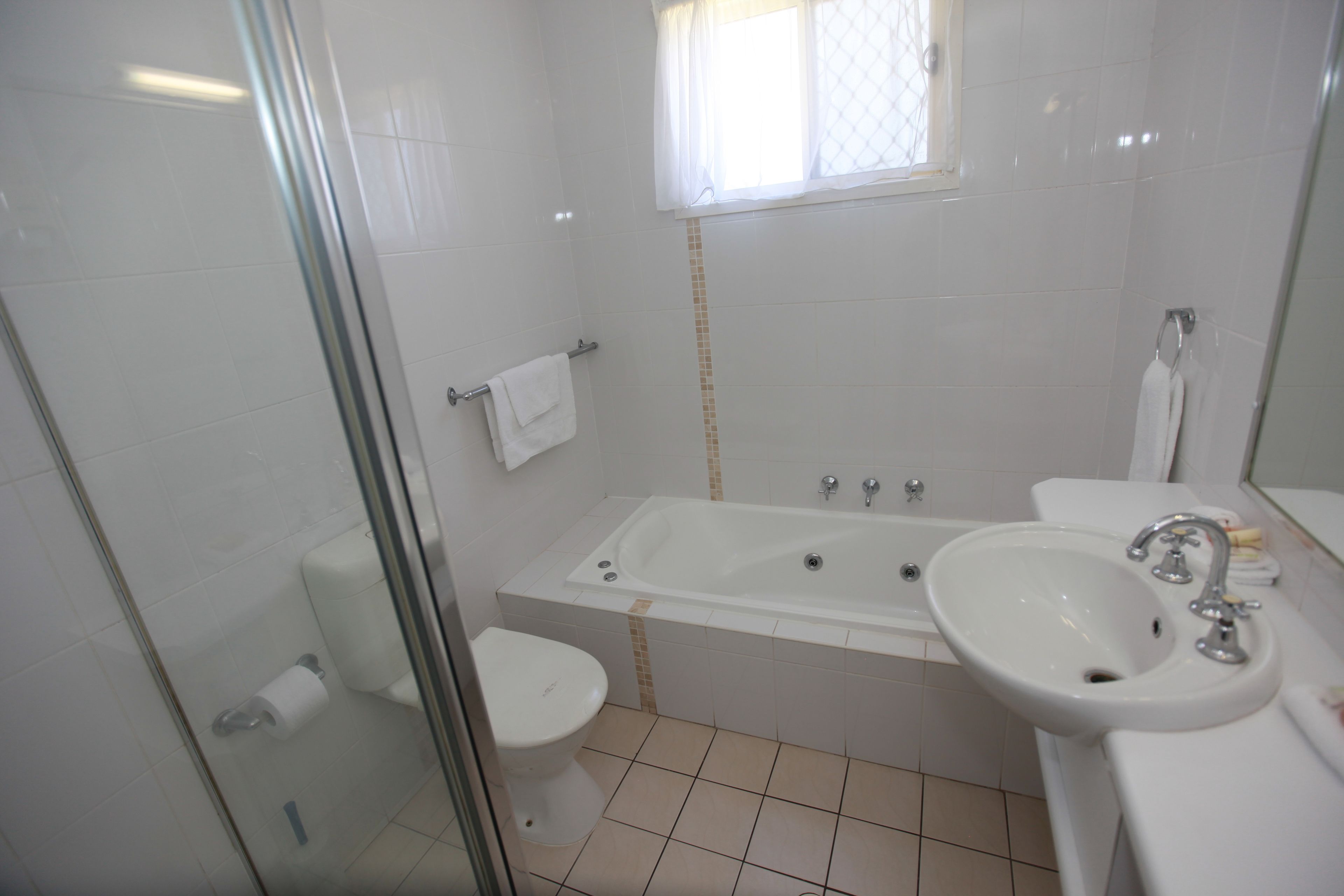 Ein Badezimmer mit Badewanne, Waschbecken, Toilette und einer Duschkabine aus Glas.