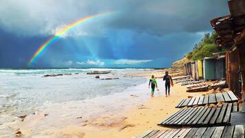A beach with wooden walkways and a rainbow in the sky.
