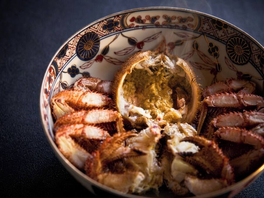 Eine Schüssel mit gekochtem Krabbenfleisch, verziert mit einem Muster, auf einer dunklen Unterlage.