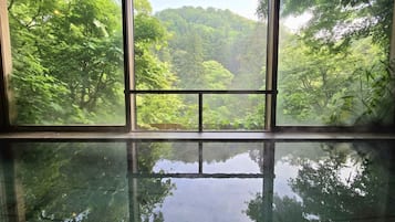 A room with a large window offering a view of a forested area.