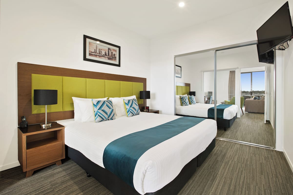 A hotel room with a large bed, a nightstand, a mirror, and a cityscape view.