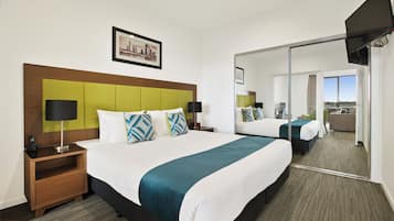 A hotel room with a large bed, a nightstand, a mirror, and a cityscape view.