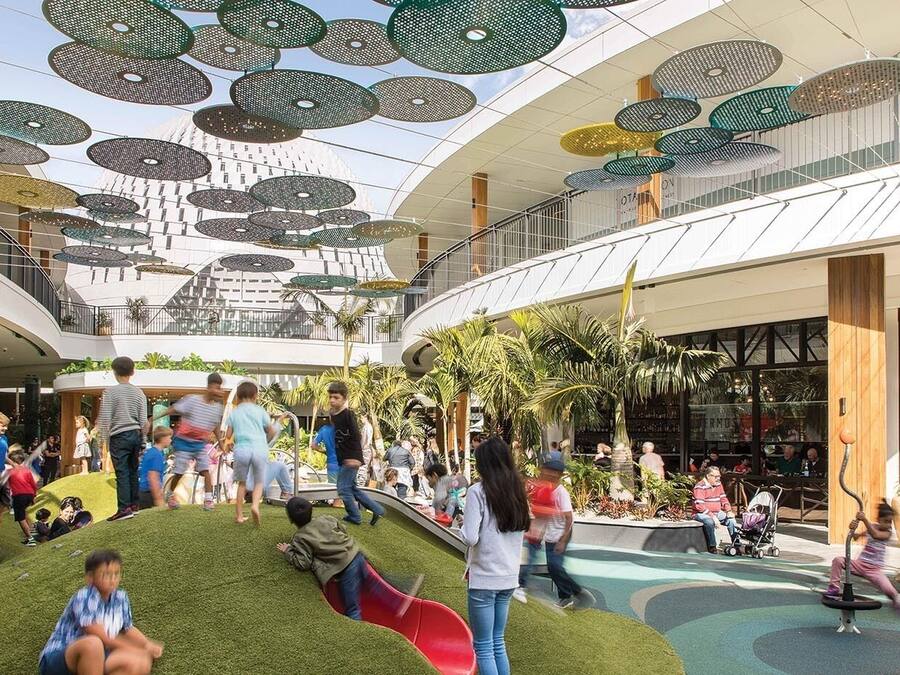 A multi-level indoor space with artificial grass, slides, and a variety of seating areas.