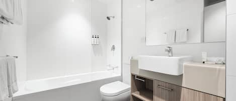 Une salle de bain moderne équipée d’une baignoire, de toilettes et d’un meuble-lavabo.