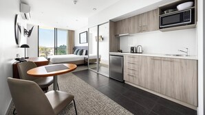 Habitación de hotel moderna con kitchenette, zona de comedor y cama con vistas.