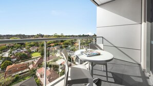 Un balcón con una mesa y sillas, con vistas a una zona residencial con casas y vegetación.