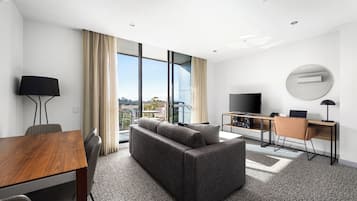 Une chambre d’hôtel moderne équipée d’un canapé, d’une table à manger, d’une télévision et d’un bureau.