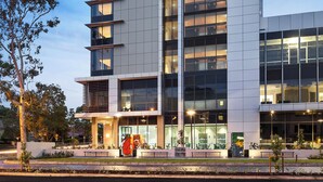 Un hotel moderno con un llamativo letrero 'WEST' en la fachada, amplias ventanas y una zona de entrada bien iluminada.
