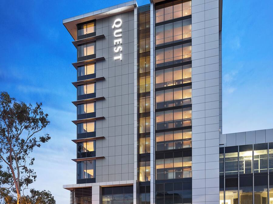 Un hotel moderno con un llamativo letrero 'WEST' en la fachada, amplias ventanas y una zona de entrada bien iluminada.