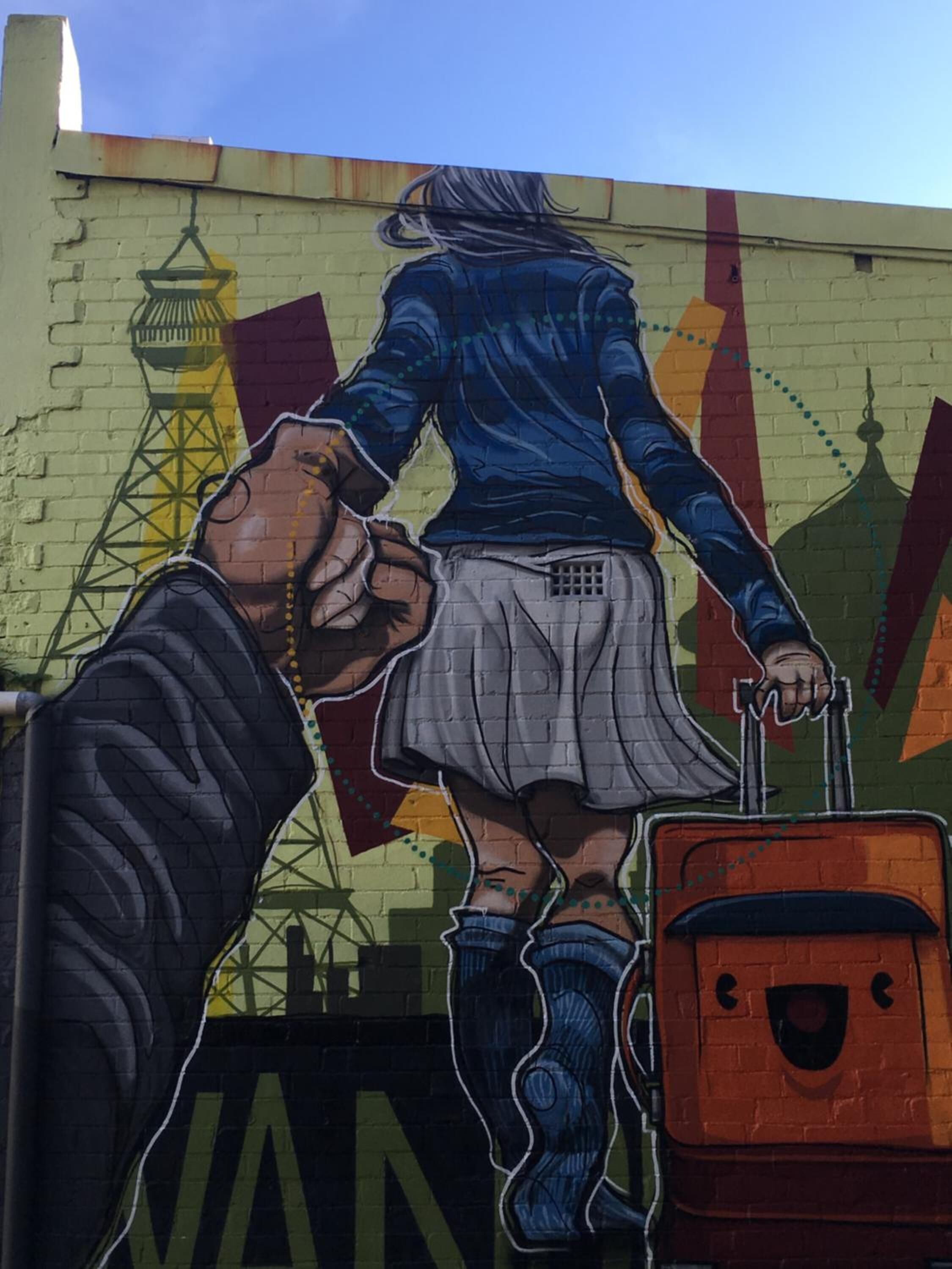 A mural of a person with a suitcase, a dog, and a building with a tower in the background.