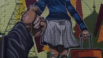 A mural of a person with a suitcase, a dog, and a building with a tower in the background.