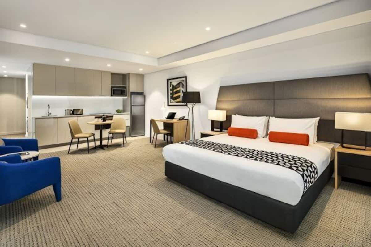 Ein Hotelzimmer mit einem großen Bett, einem Schreibtisch, einem Sessel, einer Sitzecke und einer Küchenzeile.